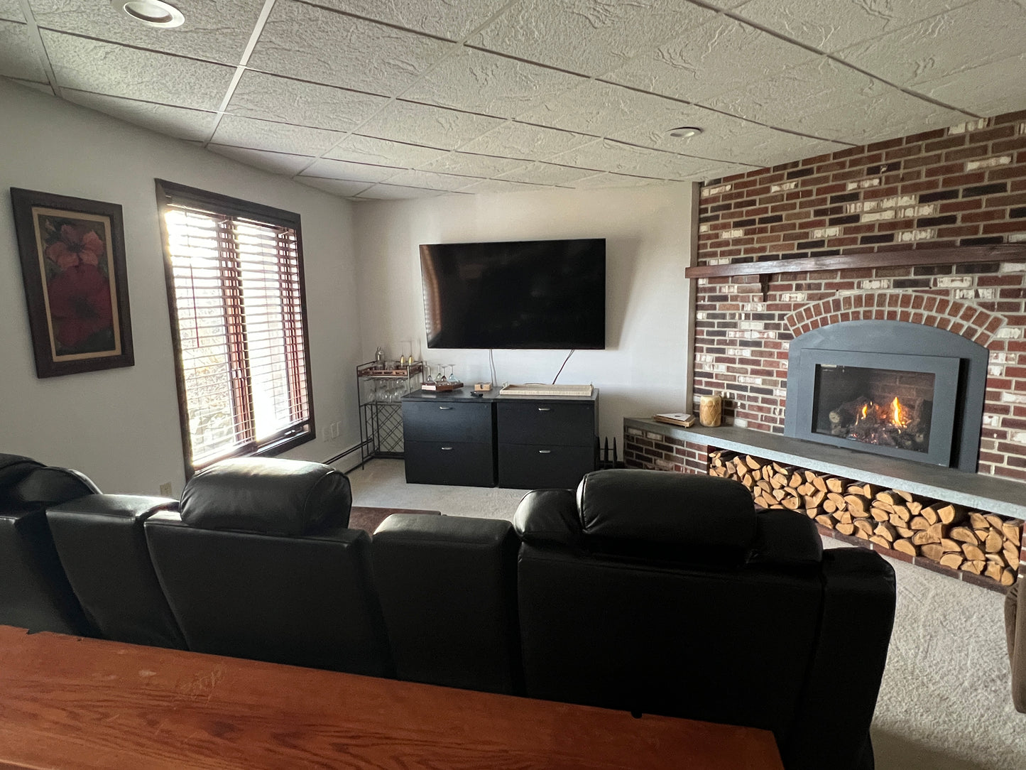 Living room with black sofa, TV, and brick fireplace. Nature View NH Estate