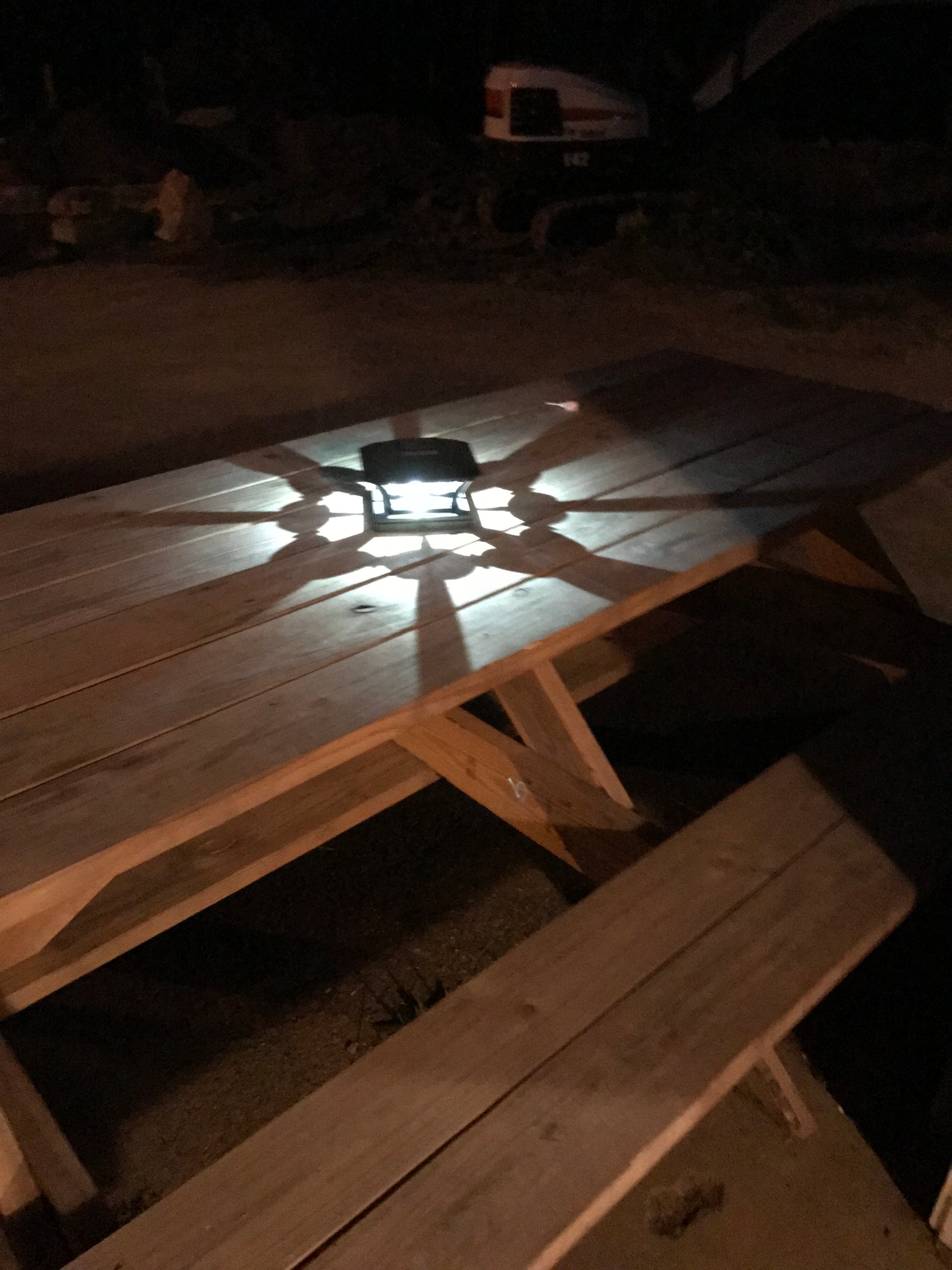 Wooden picnic table shining across the night patio