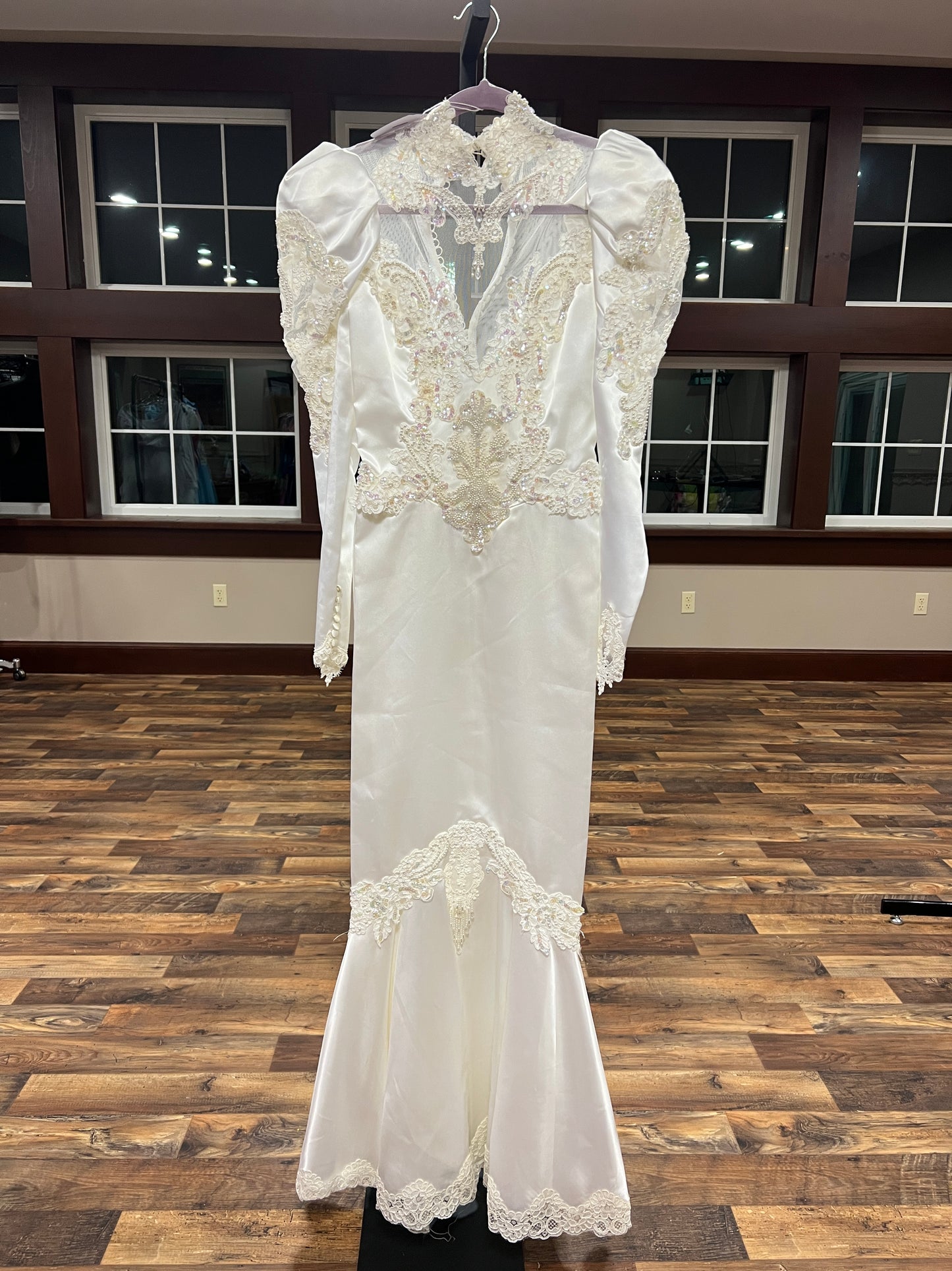 White lace wedding dress on a wooden floor with a window in the background