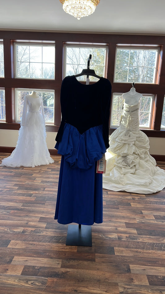 Blue dress on a mannequin in front of a window with a wooden floor.