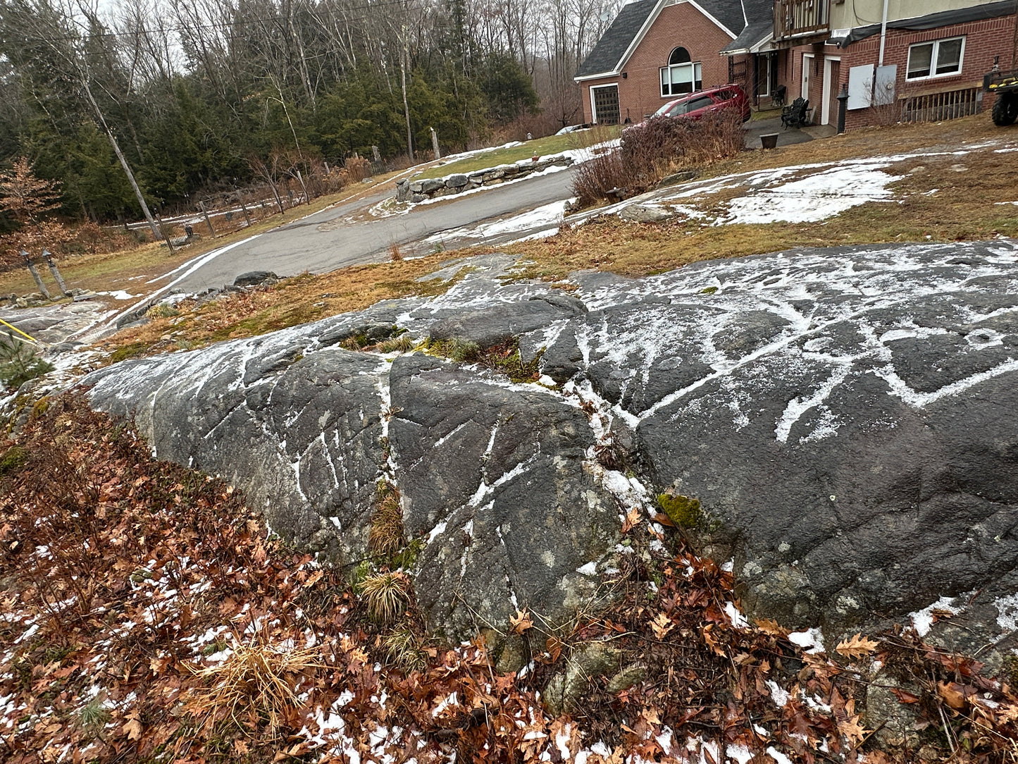 Glacial markings on the rocks with snow patches in a private estate area with a large house in the background