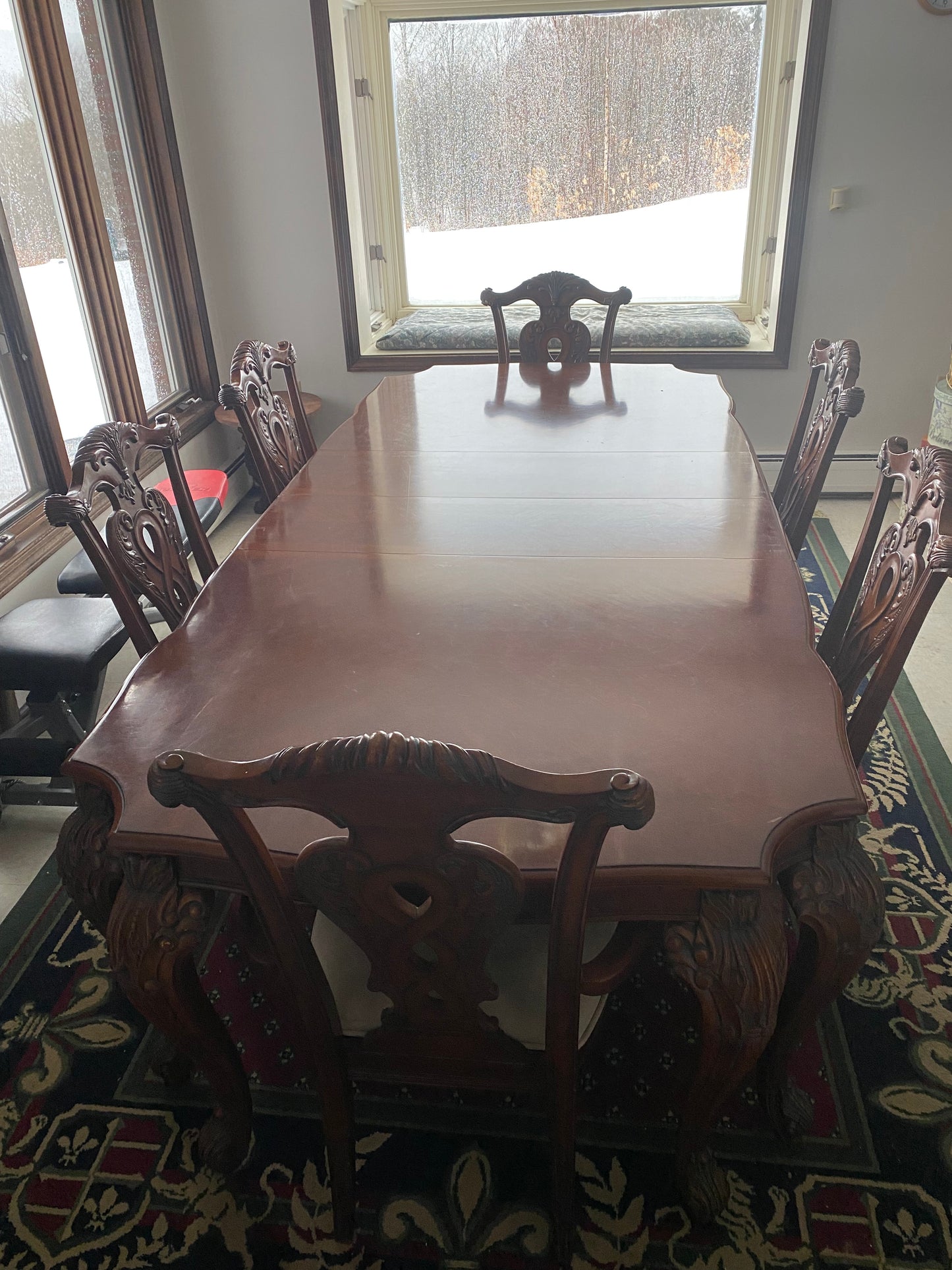 Decorative chair with intricate armrests in a room with a window and patterned rug.