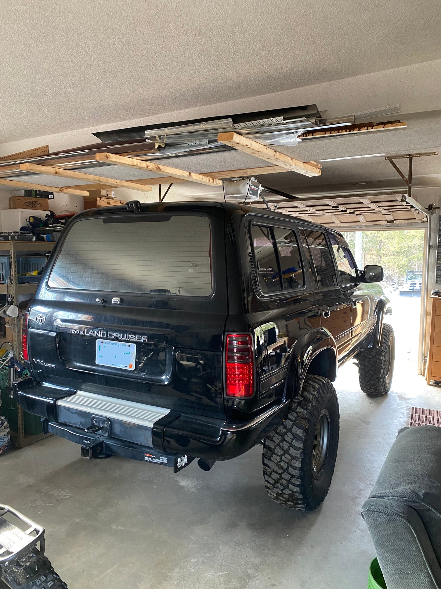 Black Toyota Land Cruiser  right hand drive diesel parked inside a garage with wooden beams and tools in the background
