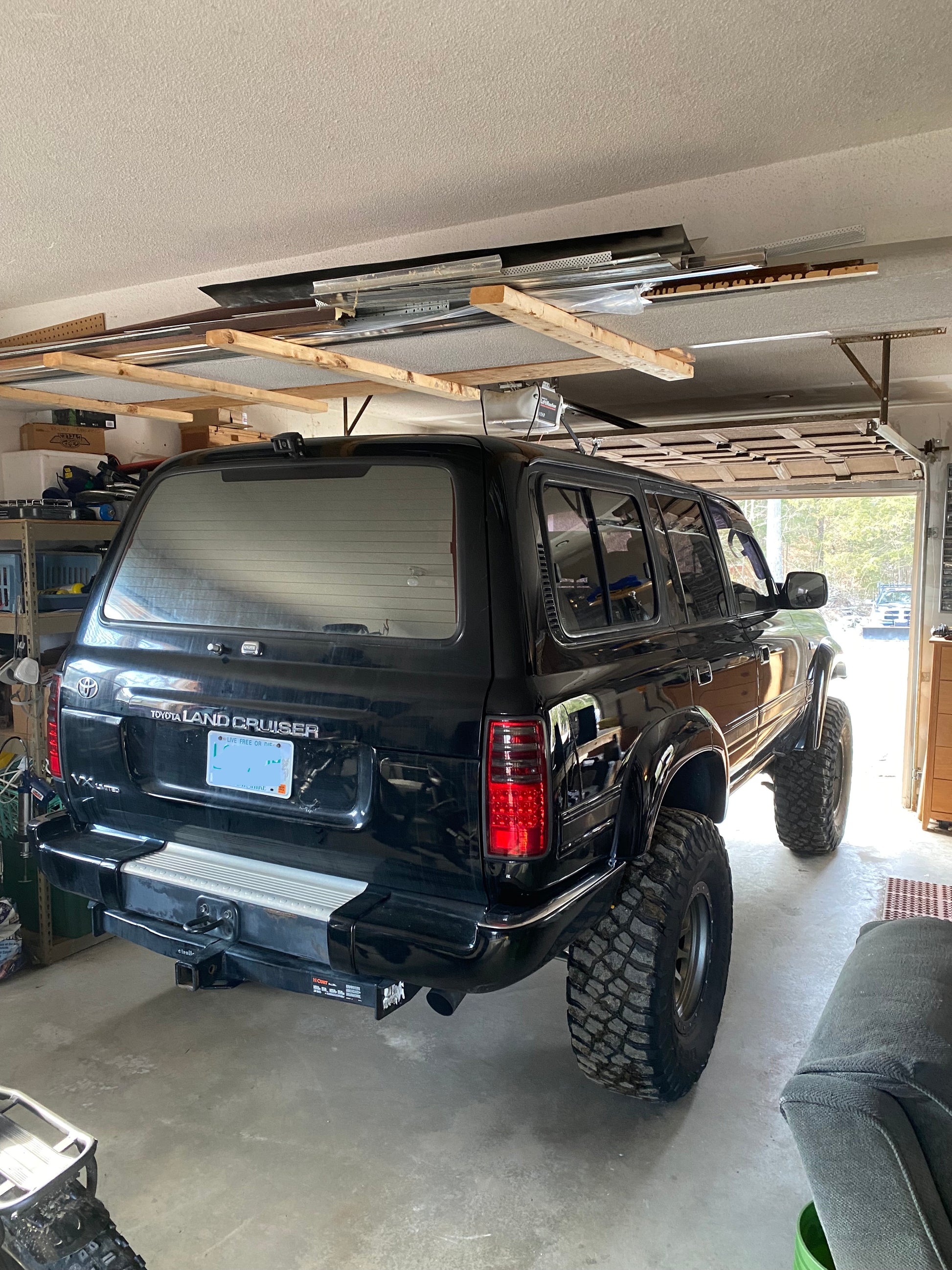 Black Toyota Land Cruiser  right hand drive diesel parked inside a garage with wooden beams and tools in the background