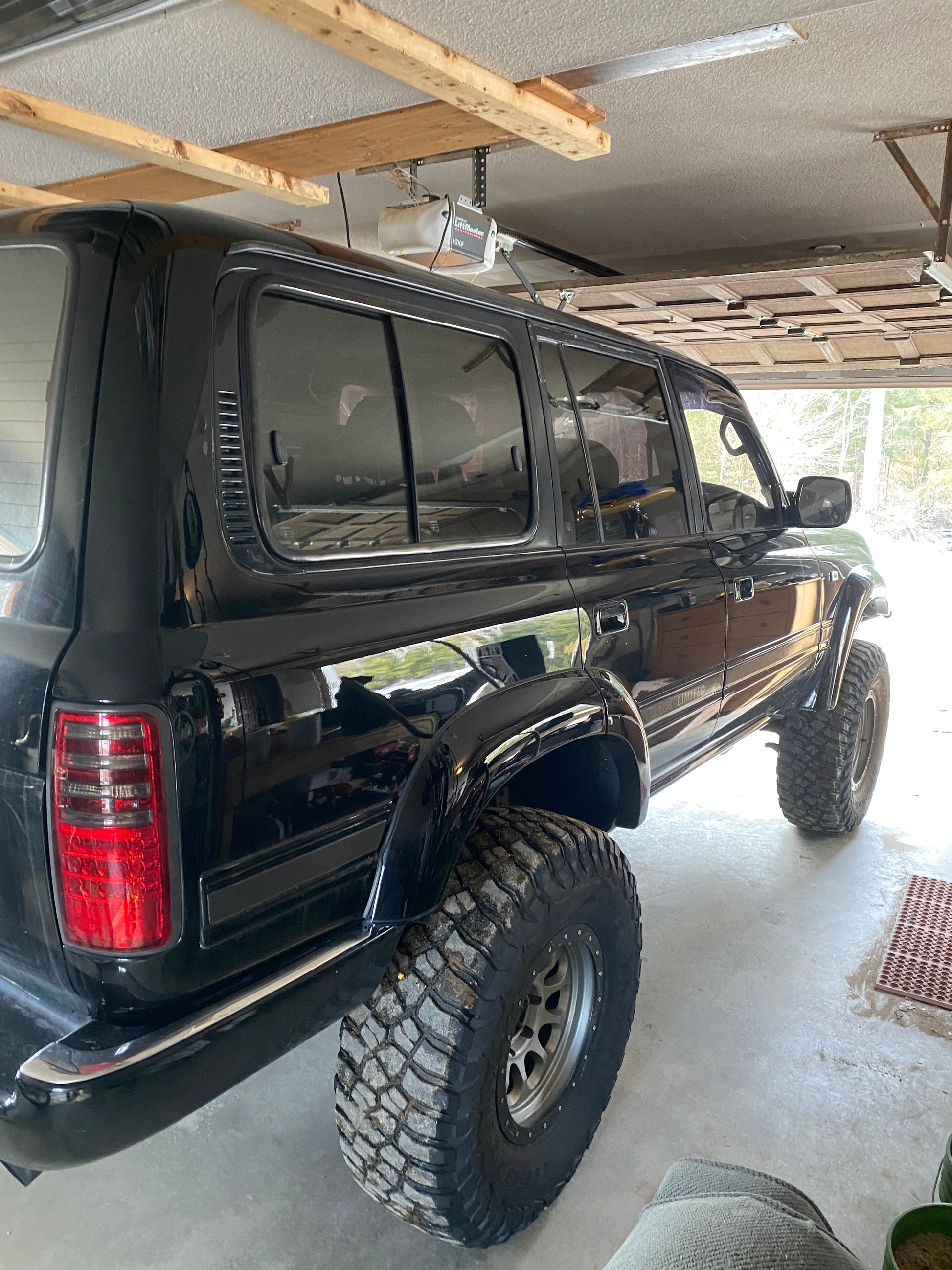 Black Toyota Land Cruiser  huge tires  on a concrete floor in a garage 