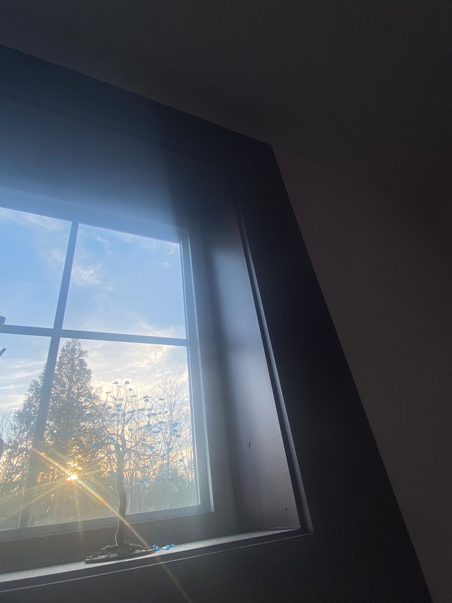 Window with sunlight shining through, reflecting on a dark ceiling.