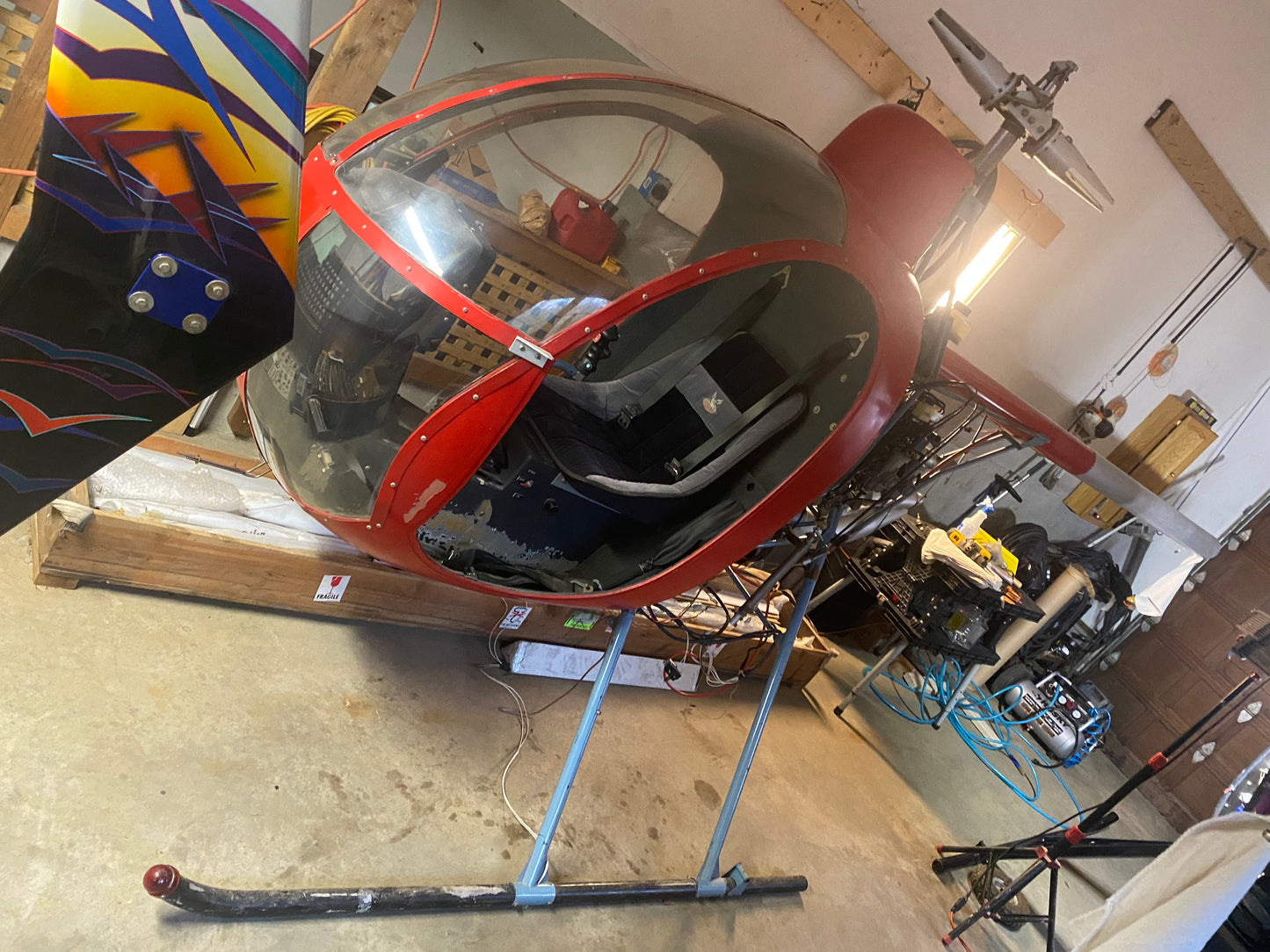 Red and black helicopter rotor head in a workshop setting
