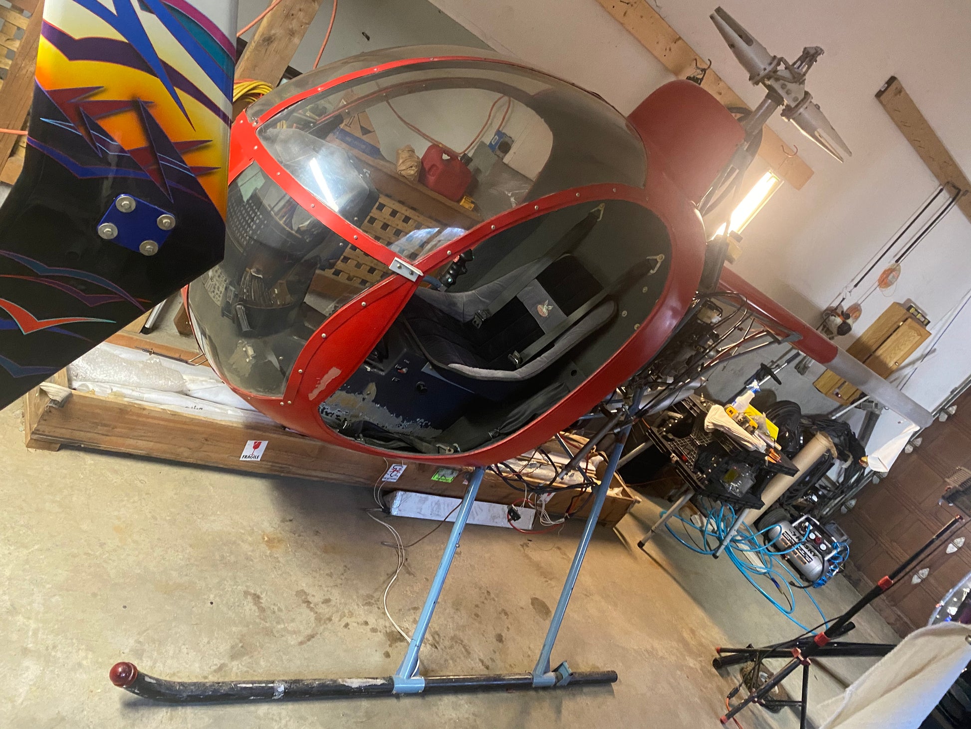 Red and black helicopter rotor head in a workshop setting