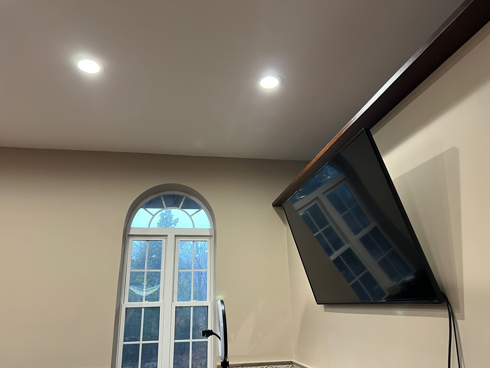 Ceiling with recessed lights and a television mounted on a wall.