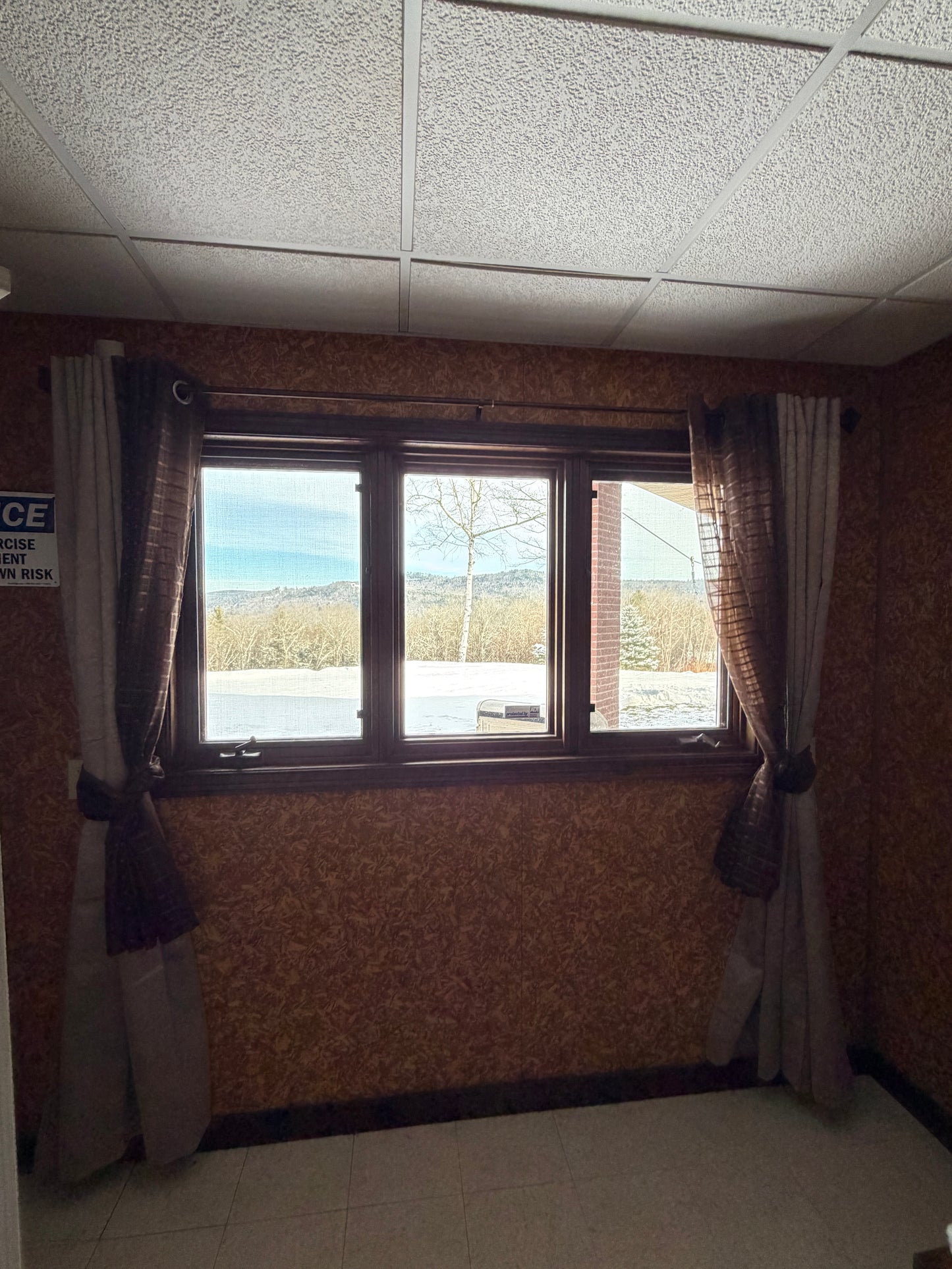 Window with floral curtains in a room with tiled walls