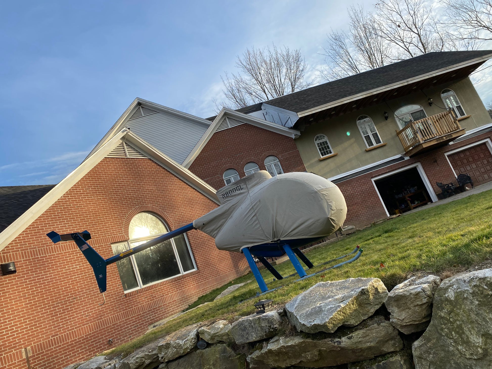 Helicopter  under a cover  balcony deck in the distance with safety net in front of a house