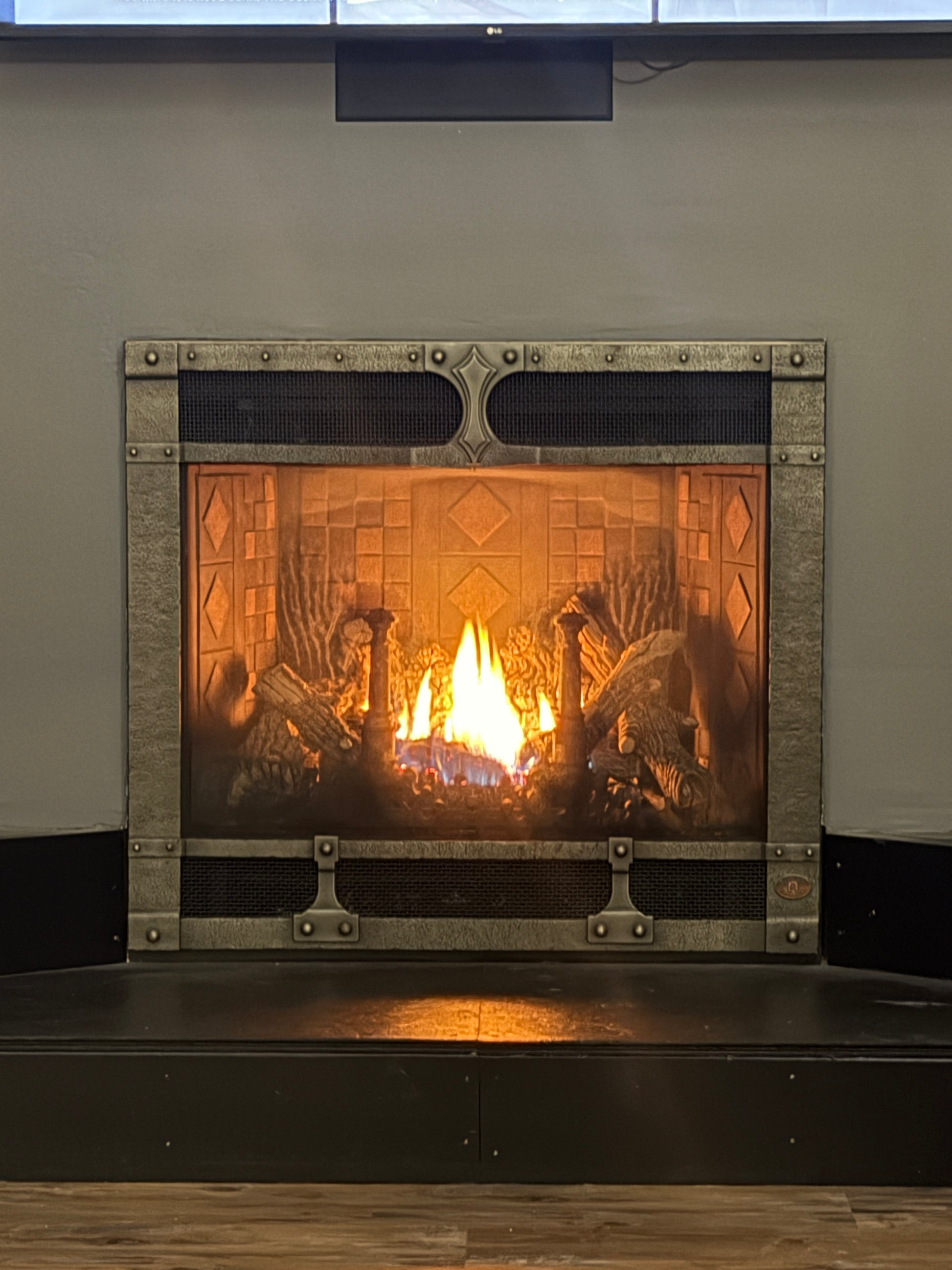 Decorative fireplace with a decorative frame on a wall.