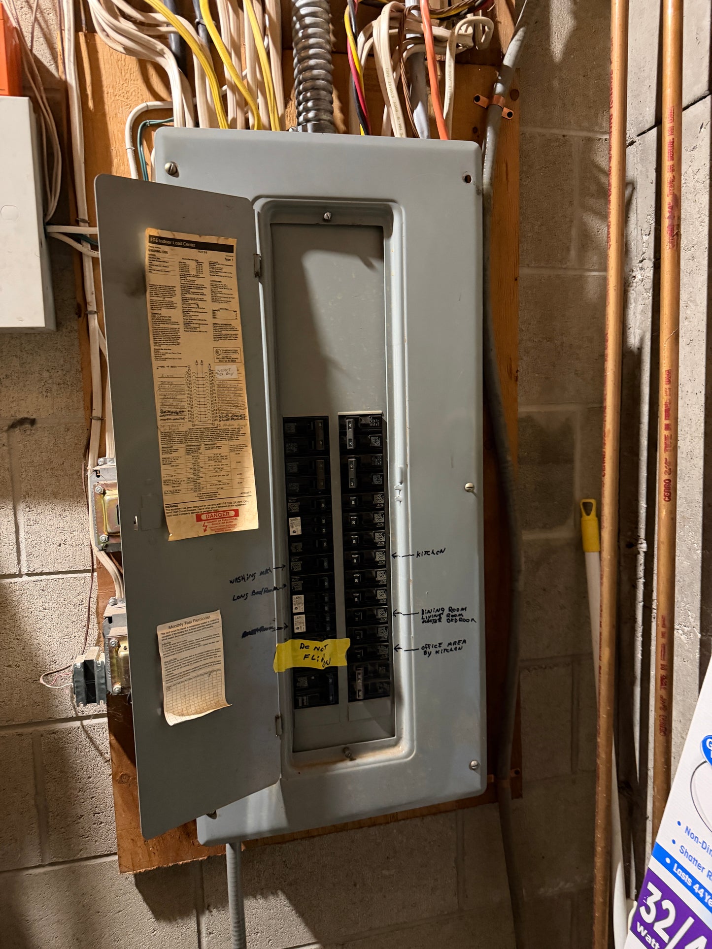 Electrical panel  in lower guest suite with wires and a piece of paper on a concrete floor