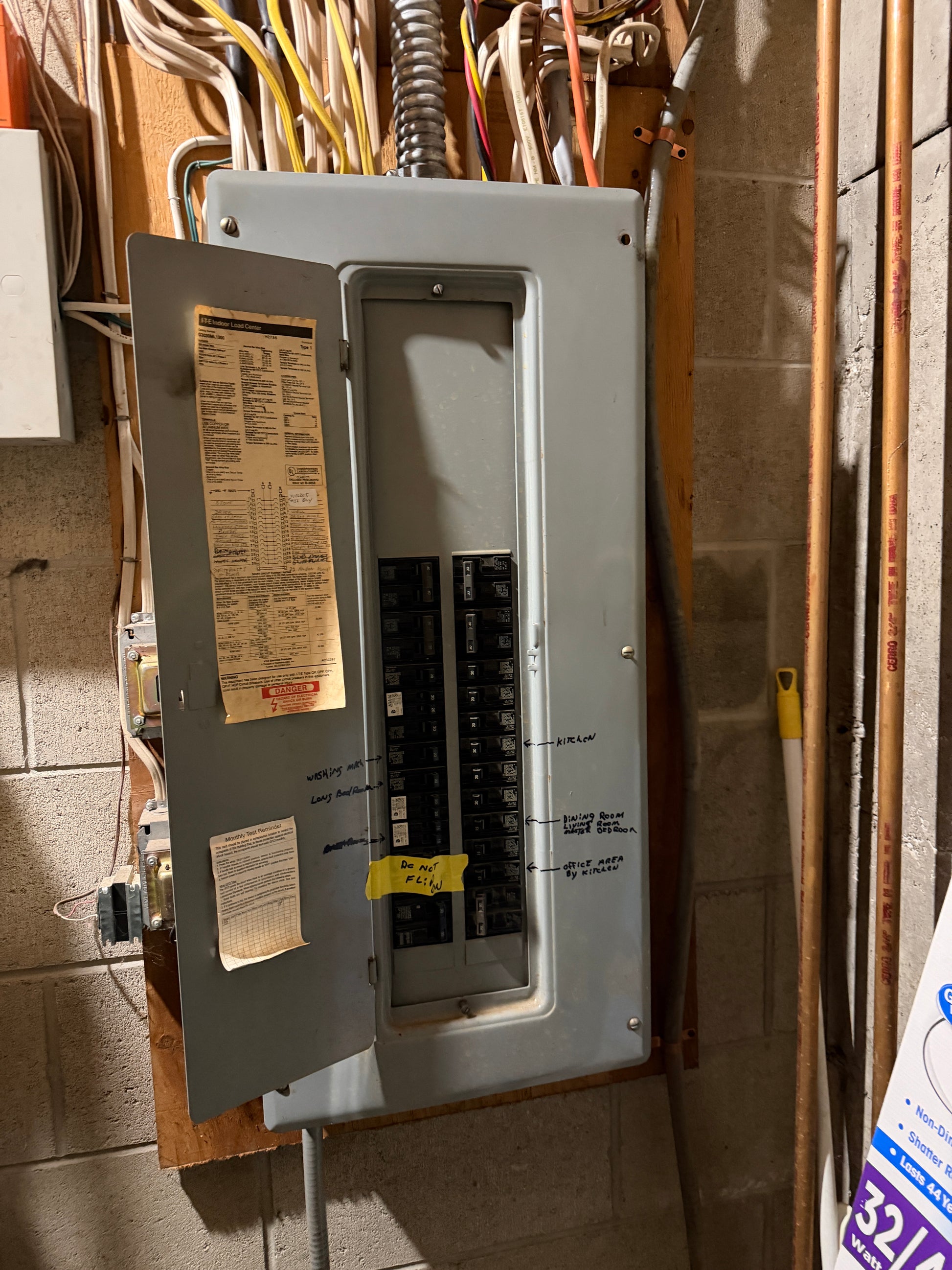 Electrical panel  in lower guest suite with wires and a piece of paper on a concrete floor