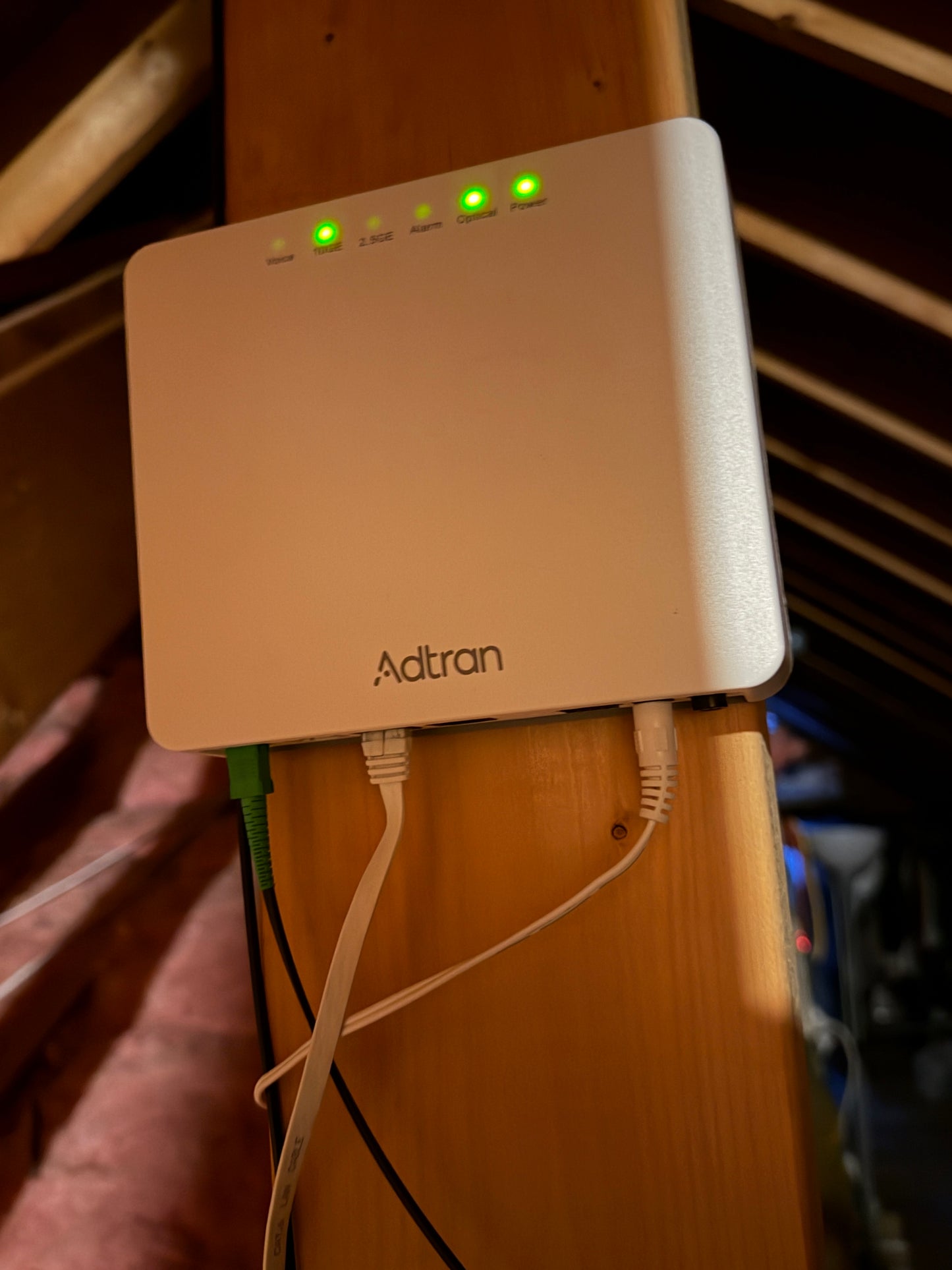 Fiber optics Adtran network device on a wooden surface with visible cables.