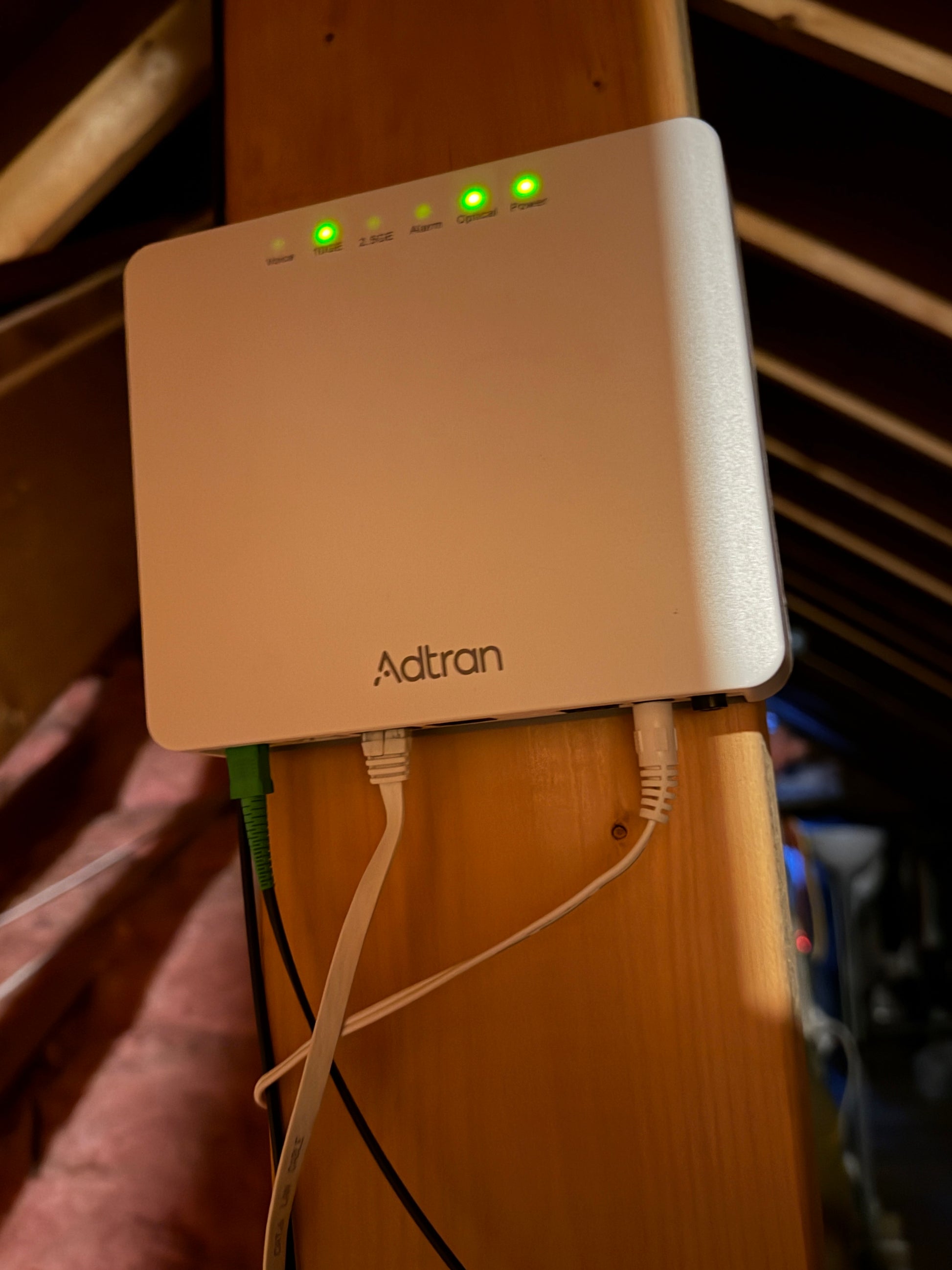 Fiber optics Adtran network device on a wooden surface with visible cables.
