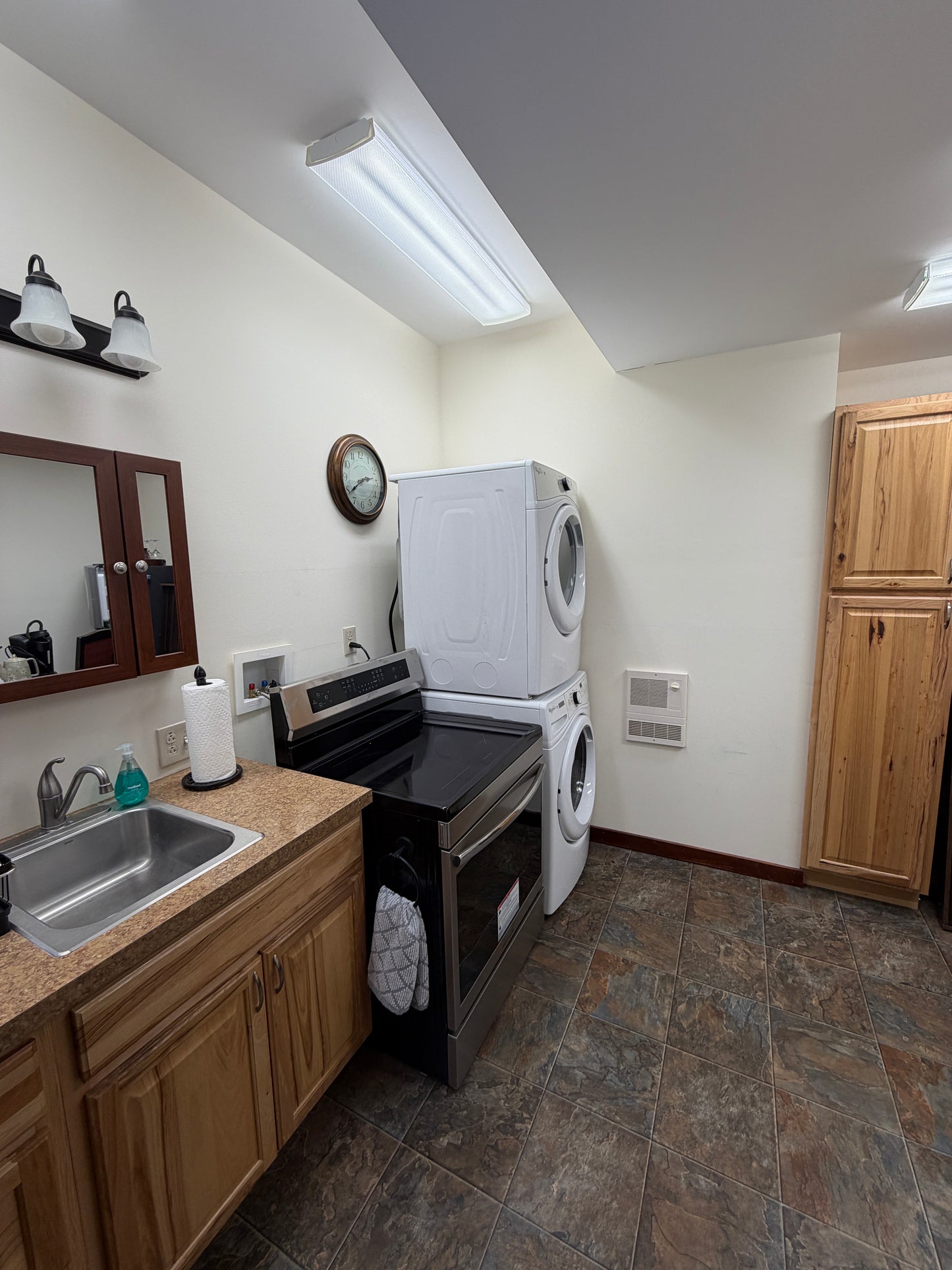 Small kitchenette with wooden cabinets, microwave, and sink. Washer and dryer