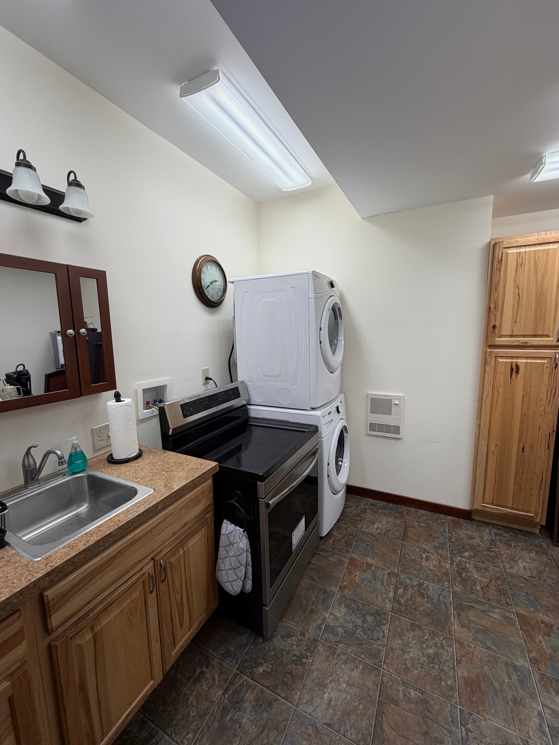 Small kitchenette with wooden cabinets, microwave, and sink. Washer and dryer