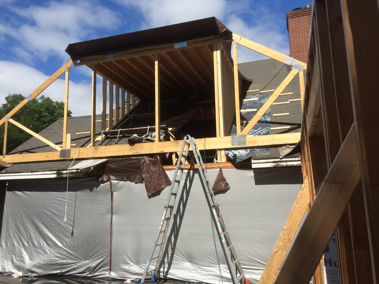 Construction site with wooden beams and a ladder on a house under renovation.