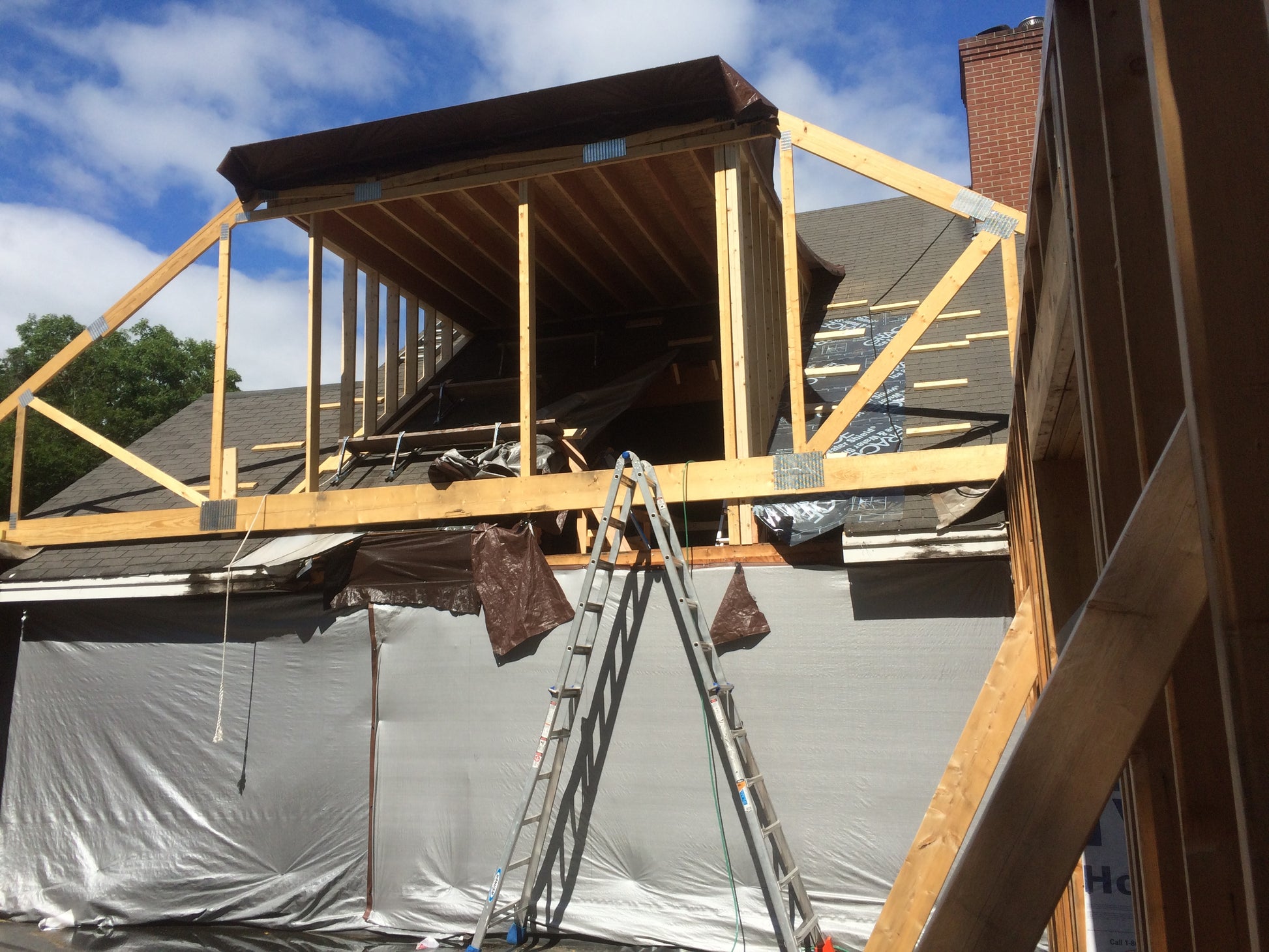 Construction site with wooden beams and a ladder on a house under renovation.