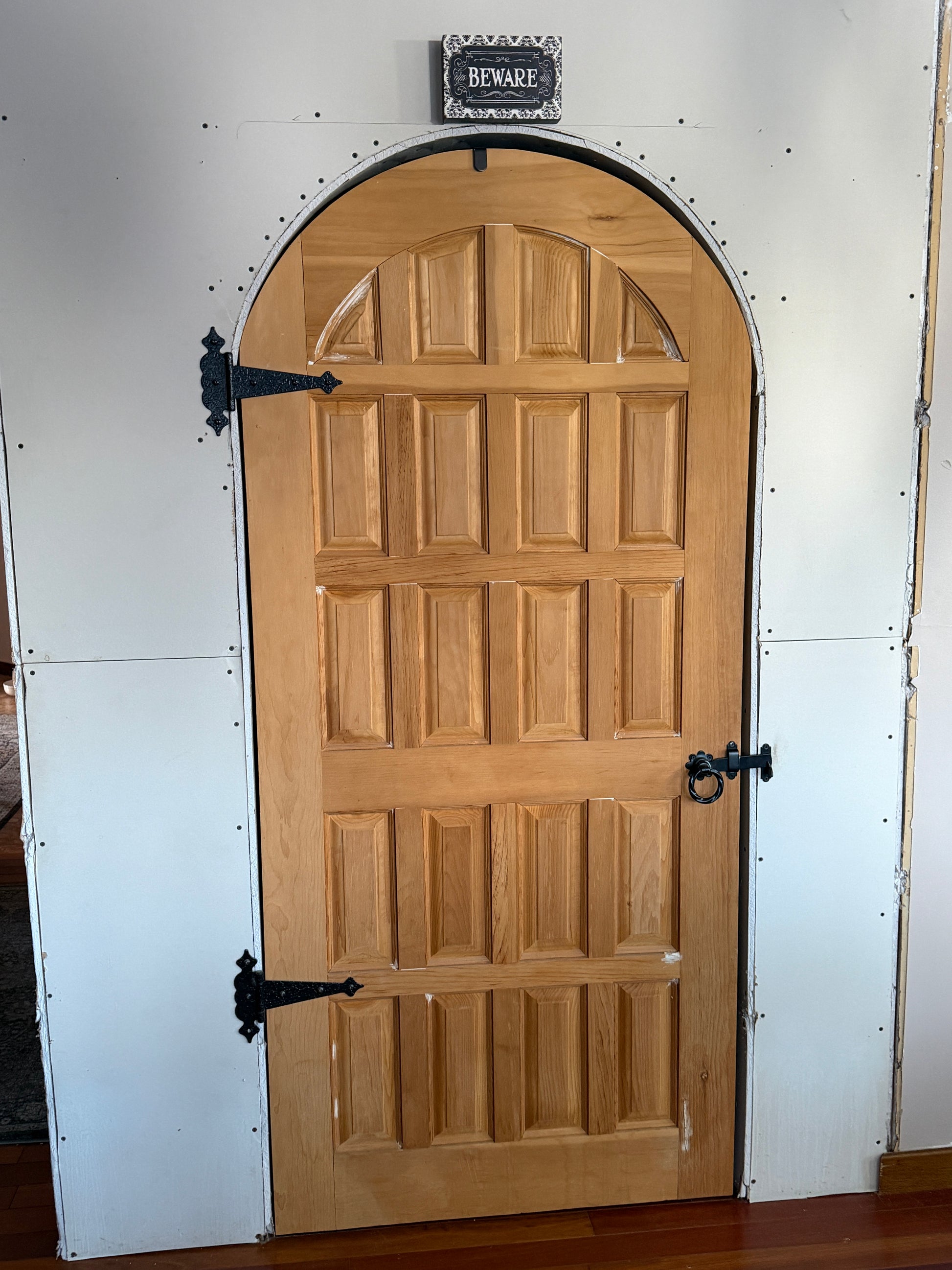Wooden arched door with metal hinges on a white background under construction