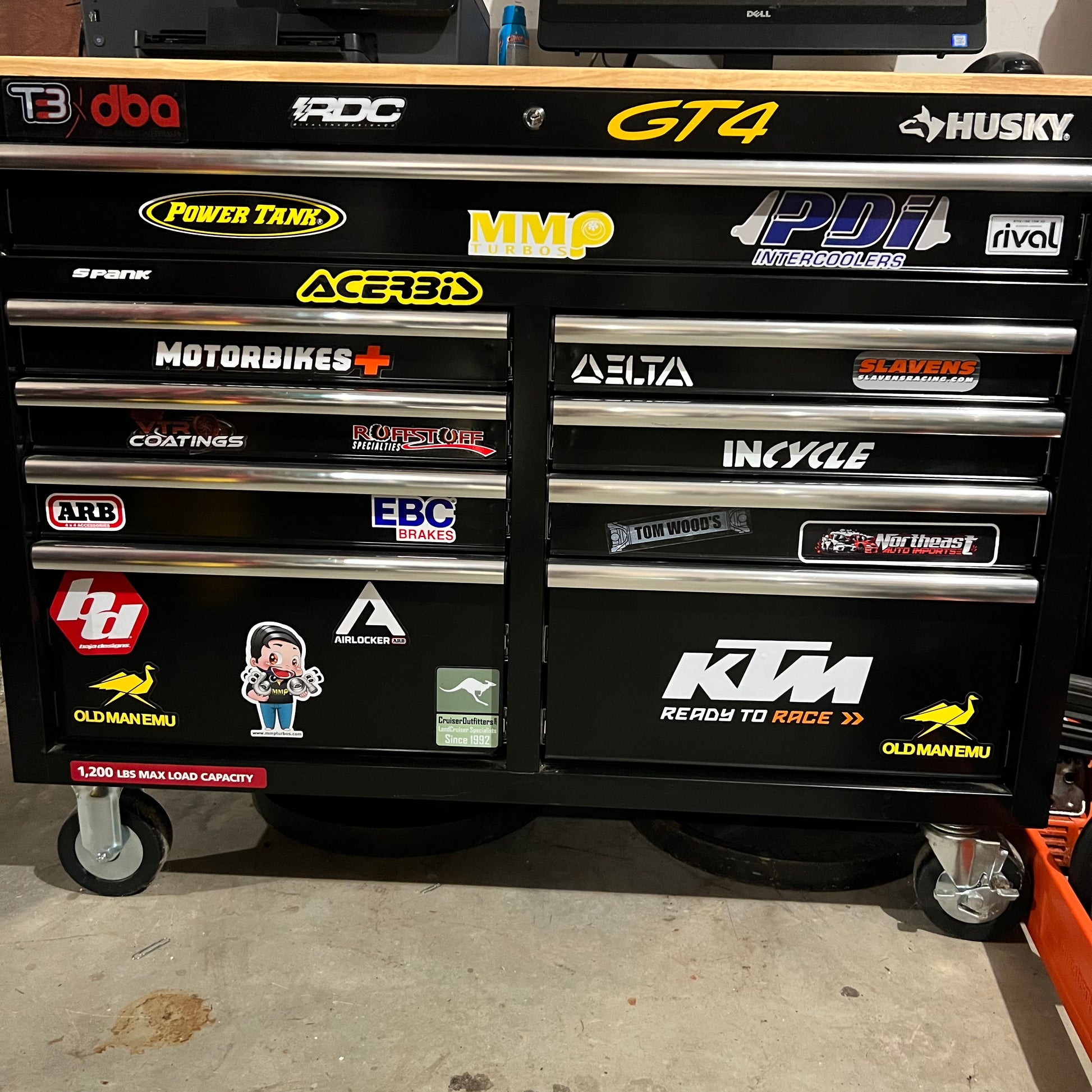 Black tool chest with various brand logos on a concrete floor.