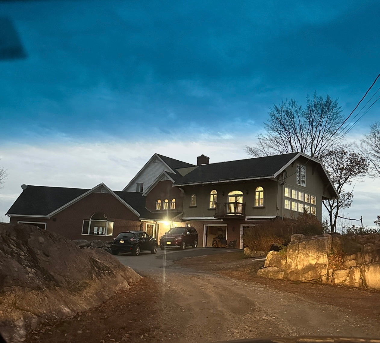 Large castle style house with ledges coming up driveway at dusk