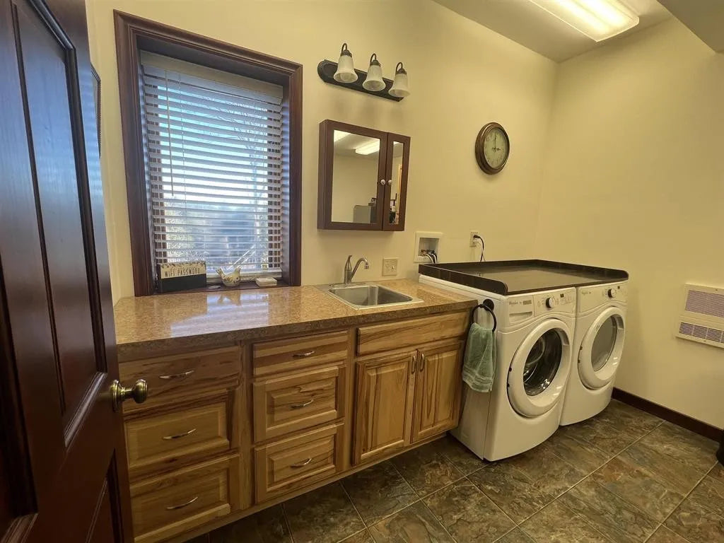Laundry room with wooden cabinets, sink, and washing machines.