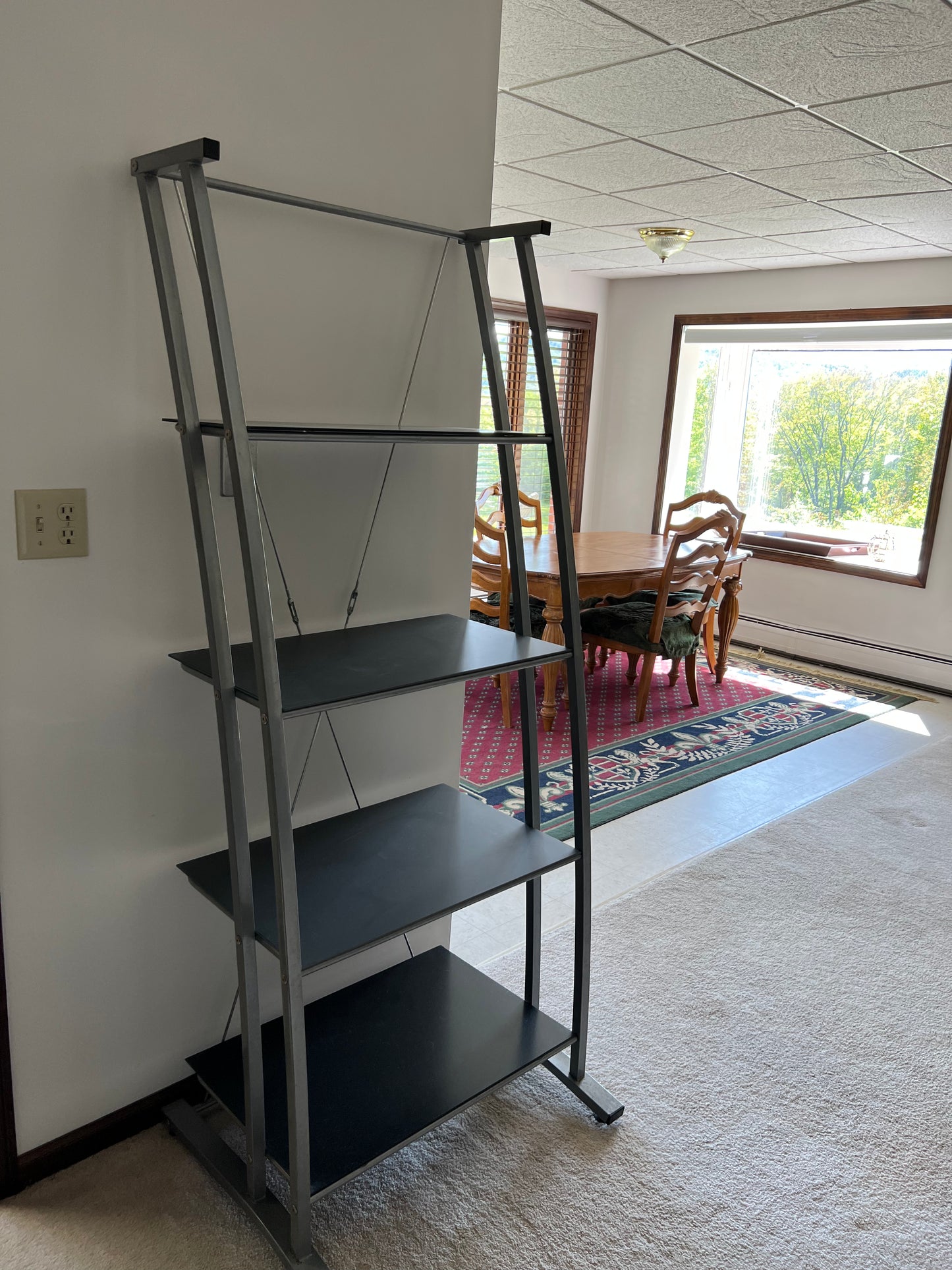 Black metal bookshelf in a room with a dining table and chairs.
