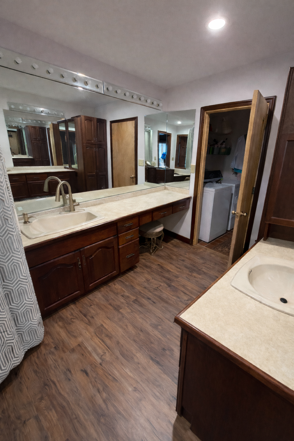 Bathroom with wooden cabinets, sink, and mirror and next to a walk in laundry room