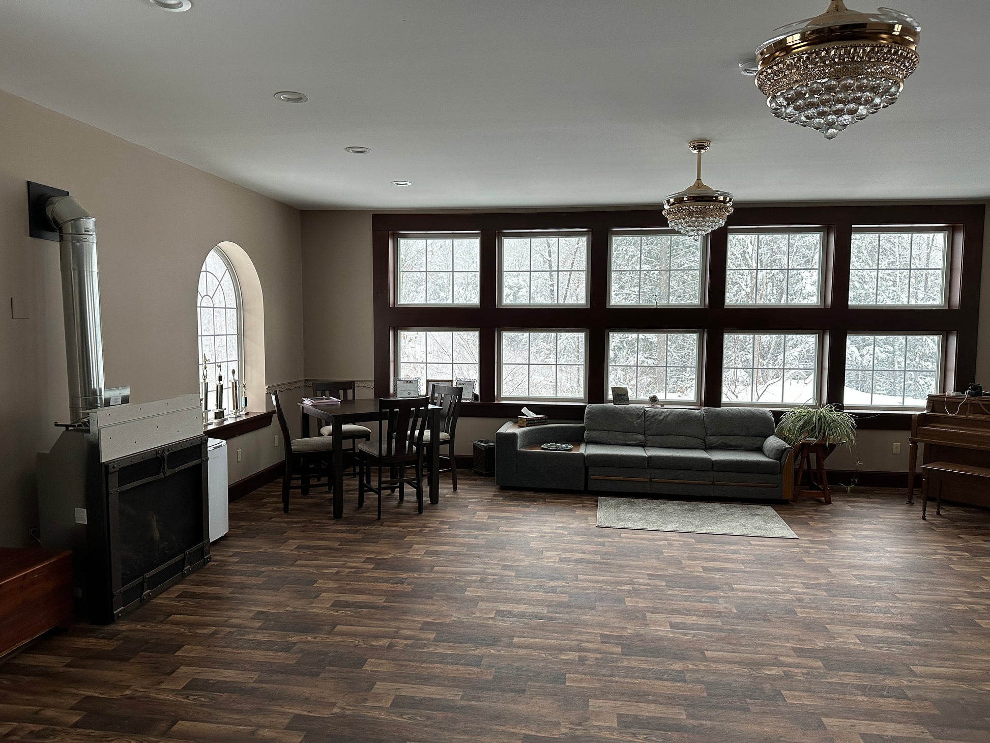 Meeting room with large windows, gray sofa, and chandelier and a pub table can seat 50 people