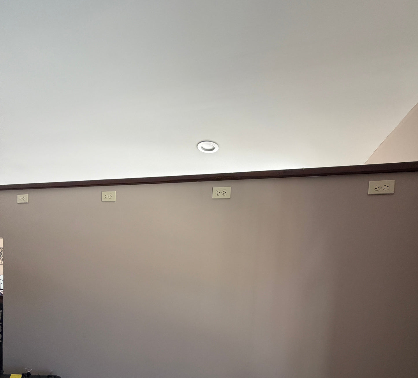 Corner of a room with a white wall, wooden desk, and various items.