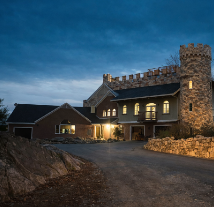 Large stone castle-style house at night with illuminated windows