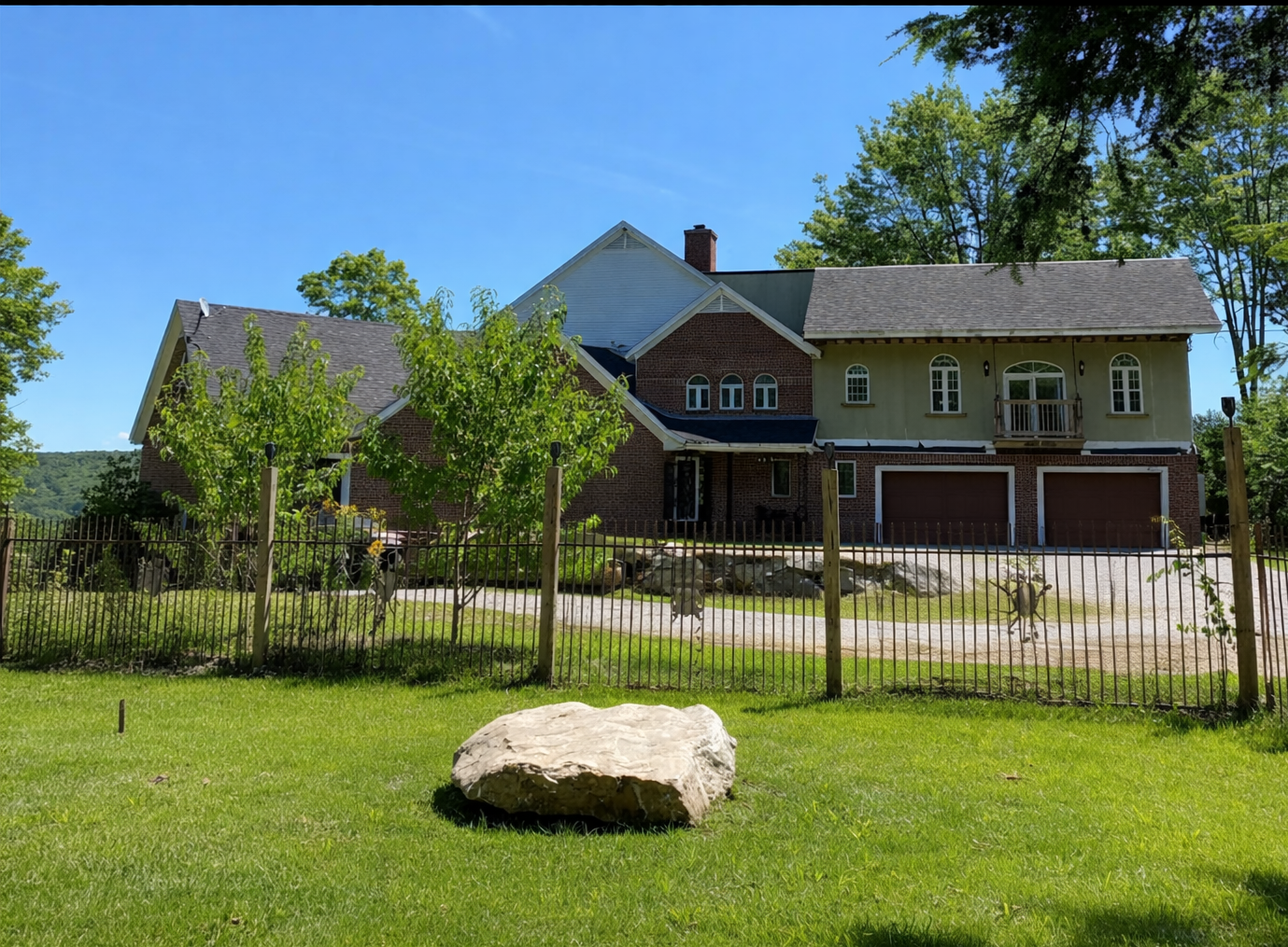 Nature View NH Estate  For Sale Keene NH. Two-story house with a large rock in front on a sunny day