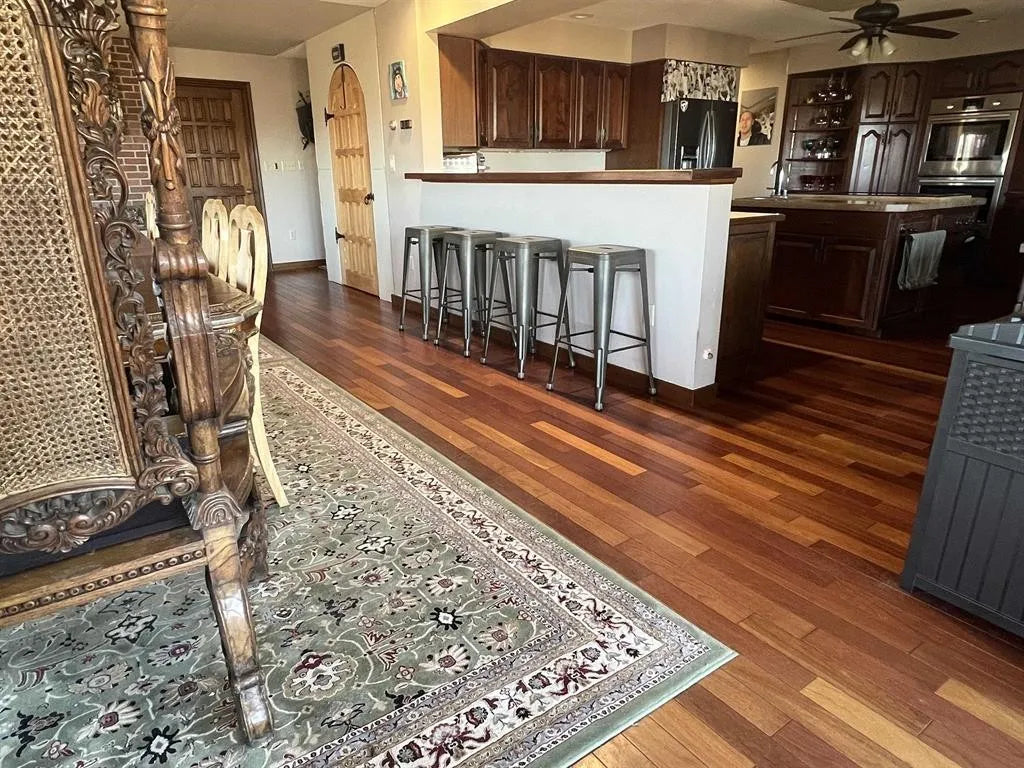 Kitchen with wooden floor, bar stools, and decorative rug.