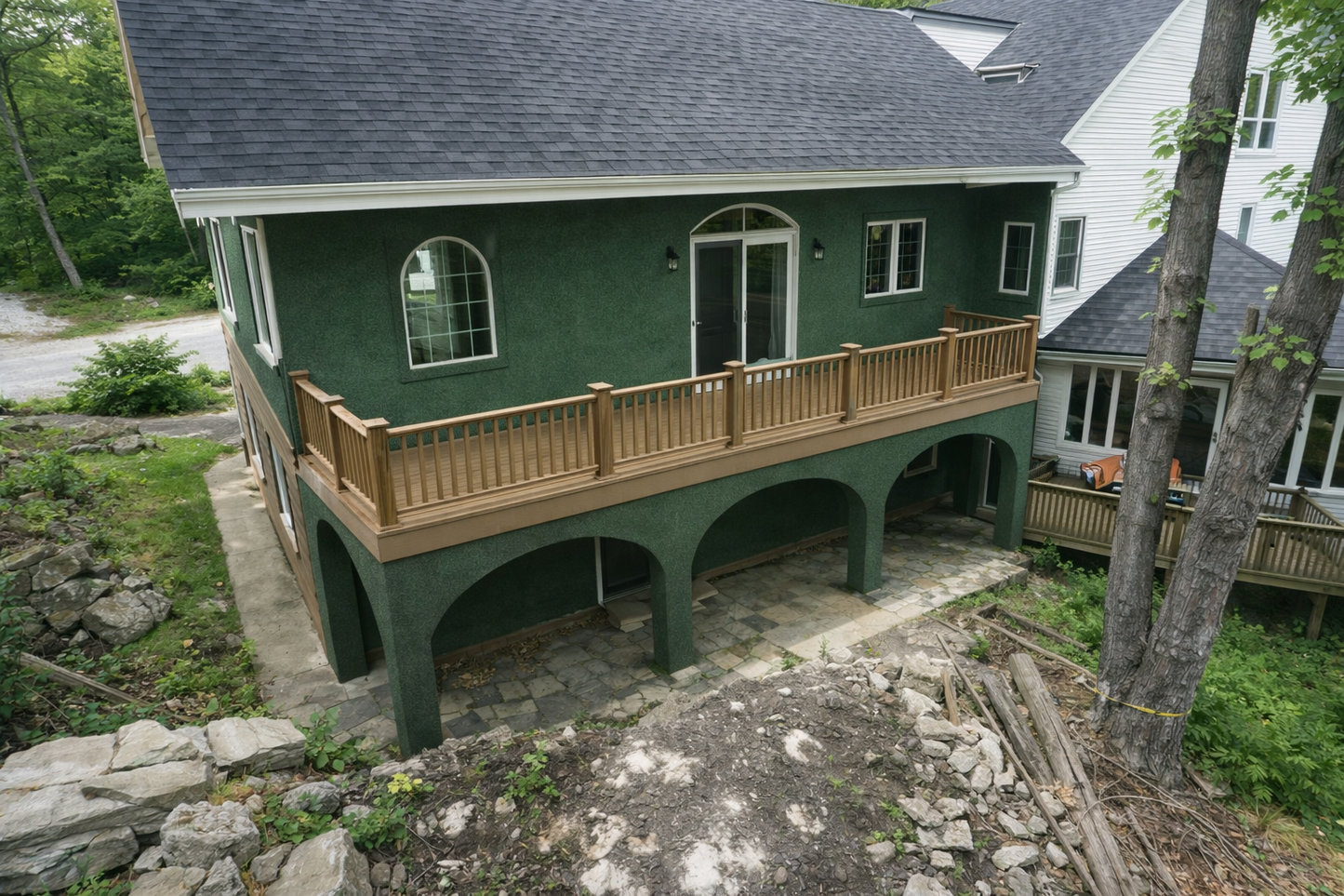 Green house with a large wooden deck in a natural setting