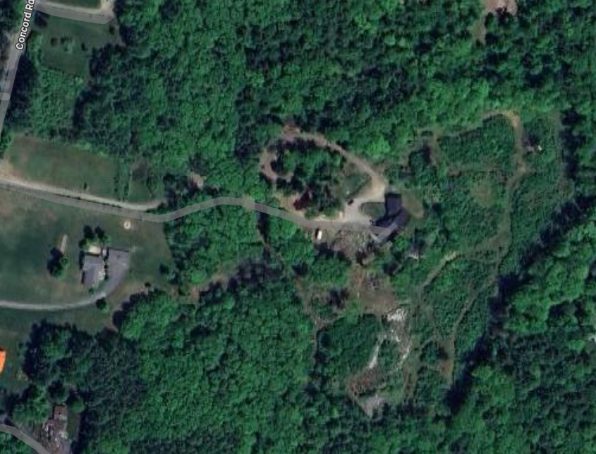 Aerial view of a forested area with a Trails  and buildings.