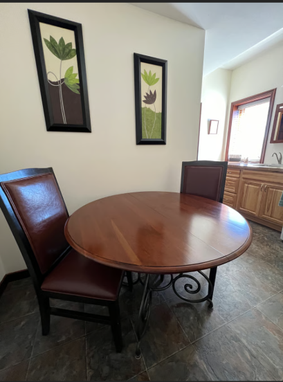 Wooden dining table with chairs in a room with framed artwork on the wall.