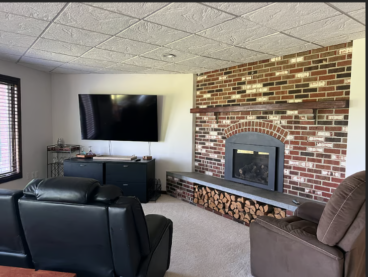 Living room with a brick fireplace, television, and comfortable seating.