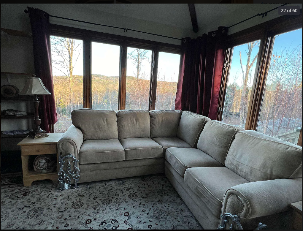 Sectional sofa in a living room with large windows and curtains. Just off master bedroom