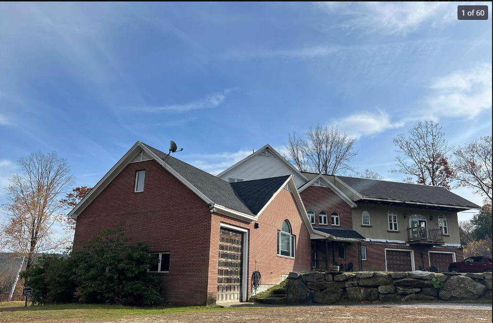 Large house with brick and stone exterior against a blue sky.
