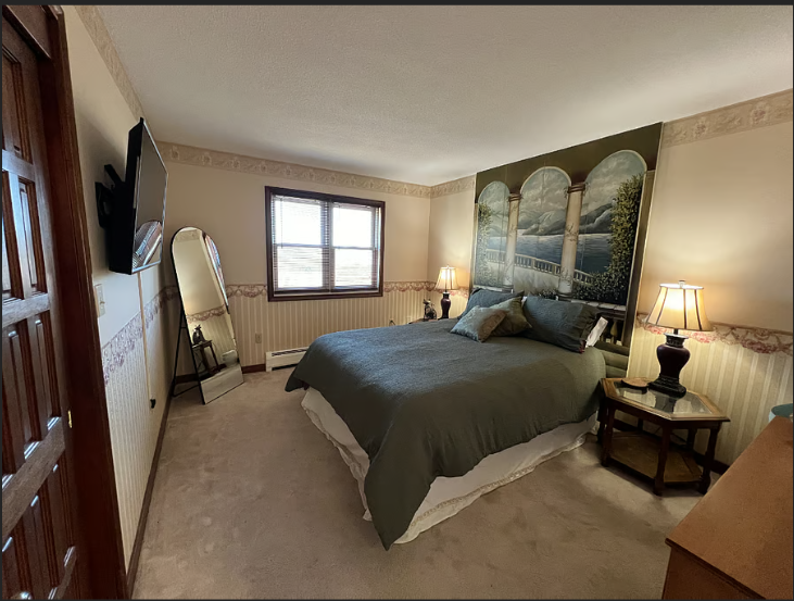 Bedroom with a bed, nightstands, and a large wall painting.