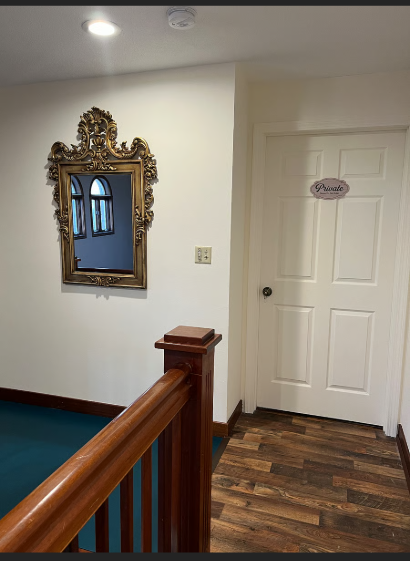 Staircase with ornate mirror and 'Private' door sign on a white wall.