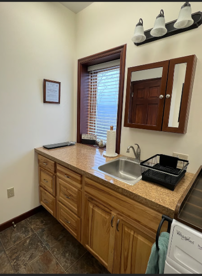 Kitchenette with sink, cabinets, and window in a room.