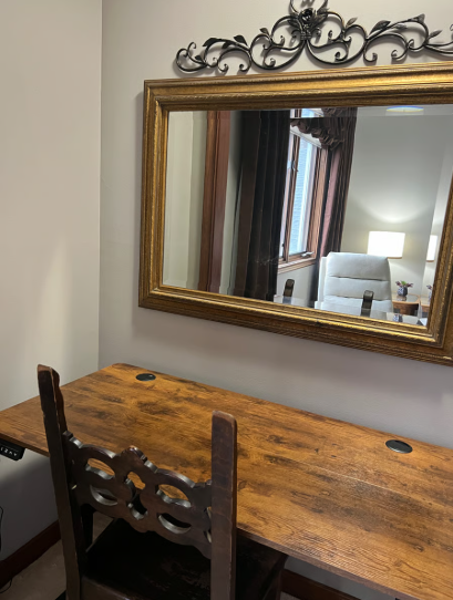 Wooden desk with chair and decorative mirror on wall
