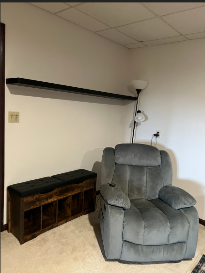Gray recliner chair in a room with a wooden bench and ceiling lights.