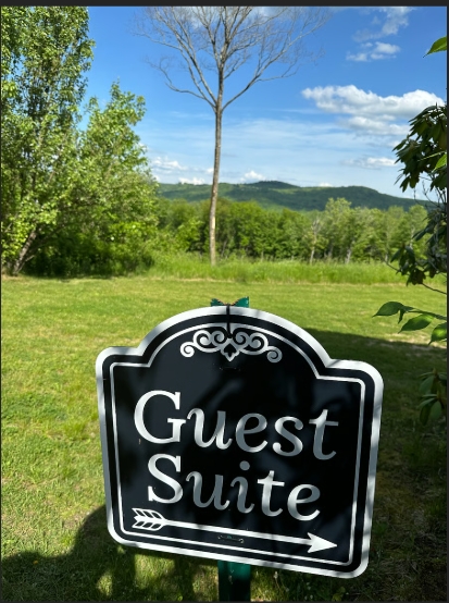 Guest Suite sign in a grassy area with trees and mountains in the background