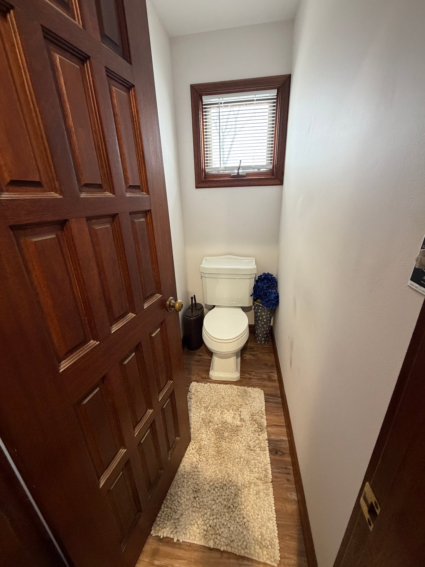 Bathroom with wooden floor, toilet, and window