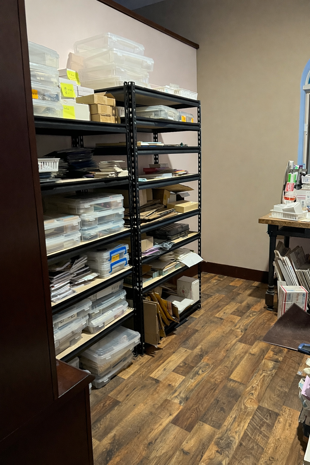 Storage room with shelves filled with boxes and containers on a wooden floor.