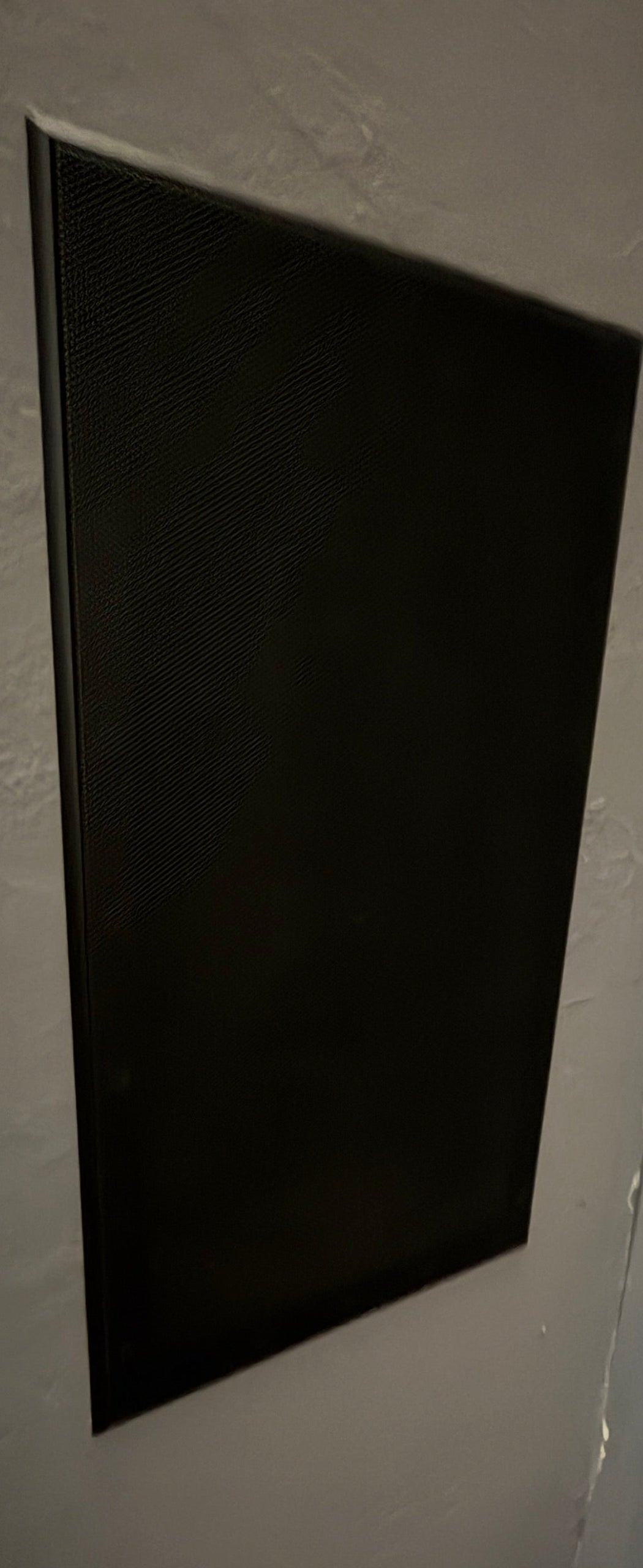 Rectangular sonance speakers on a gray wall with a partially visible green object at the bottom.